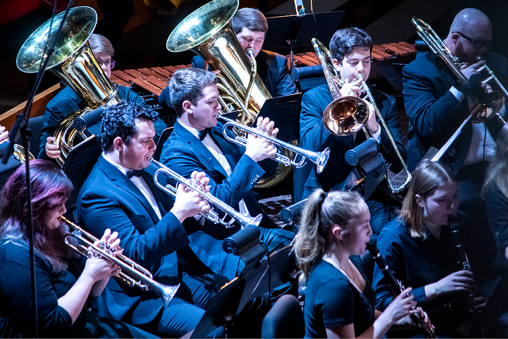 A photo of students performing their instruments at a music concert.